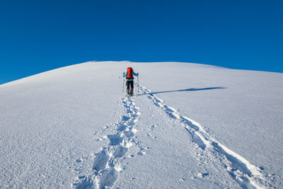 Man skiing on snowcapped mountain against clear sky