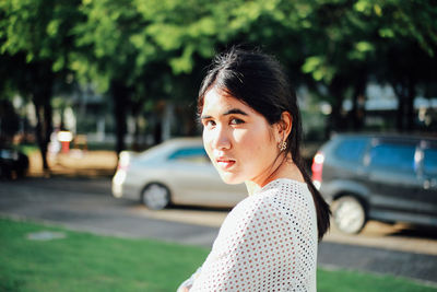 Portrait of woman standing against cars in city