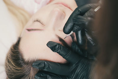 Hand of woman tattooing eyebrow of patient