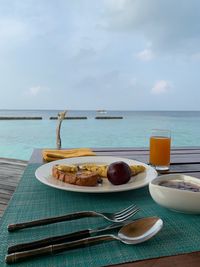 Breakfast on table by sea against sky