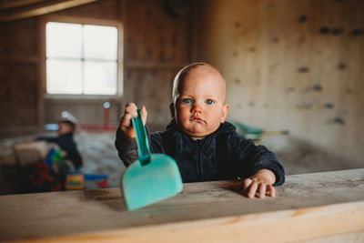 Little boy at indoor playground with shovel playing with sand winter