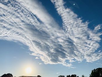 Low angle view of sunlight streaming through clouds