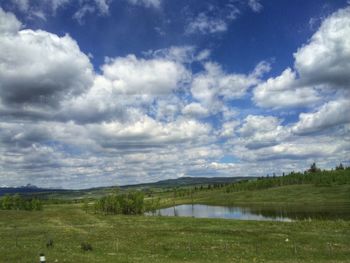 Scenic view of grassy field against cloudy sky