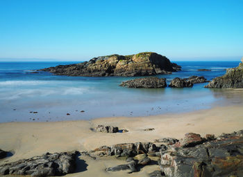 Scenic view of beach against clear blue sky