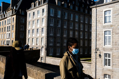 Woman standing by building in city