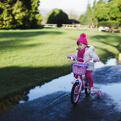 Cute girl riding bicycle on road in park