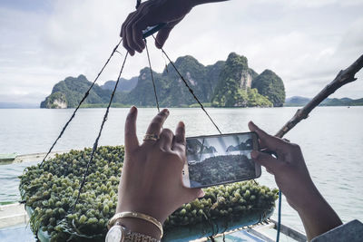 Tourist hand using a mobile phone to take pictures of seaweed, in ao luek, krabi, thailand