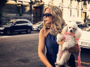 Woman with dog standing on street in city