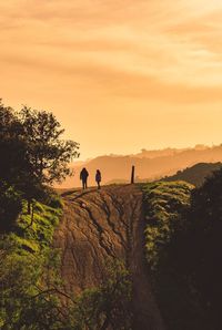 People on mountain against sky during sunset