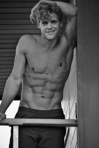 Portrait of shirtless man standing against wall