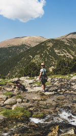 Rear view of man on rock against sky