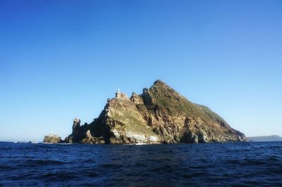 Rock mountain at sea against sky