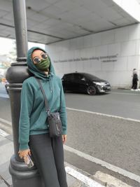 Full length of woman standing against car in city