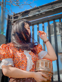 Midsection of woman holding umbrella while standing against built structure