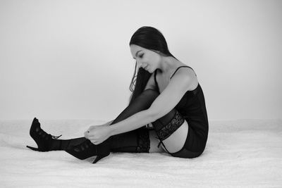 Side view of woman sitting against gray background