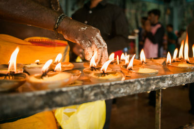 Cropped hand of man burning candles in temple