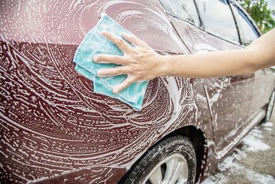 Cropped hands of man cleaning car