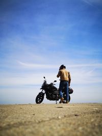 Side view of man riding push scooter on road against sky