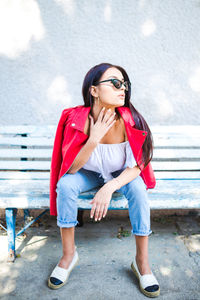 Portrait of young woman standing against wall