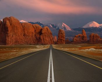 Empty road by mountains against sky