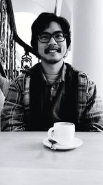 Happy young man with coffee at table