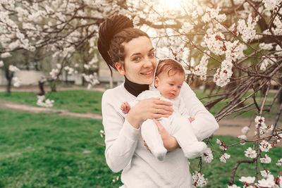 Portrait of smiling woman holding daughter in park