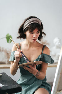 Female painter holding palette and paintbrush at art studio