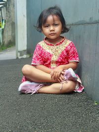 Portrait of cute boy sitting on footpath