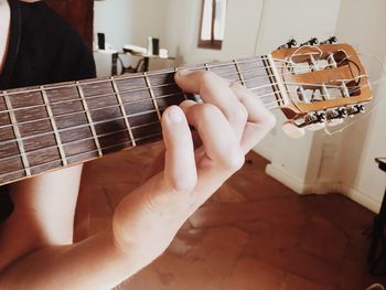 Close-up of man playing guitar at home