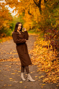 Young woman standing against trees