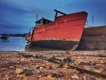 Abandoned boat moored on beach against sky