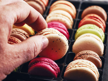 Cropped hand holding colorful macaroon on table