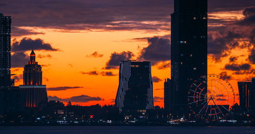 Modern buildings in city against sky during sunset