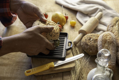 Cropped hands of man preparing burger on table