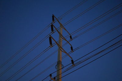 Low angle view of electricity pylon against blue sky