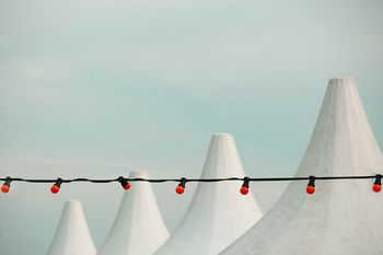 Low angle view of red light bulbs hanging against built structures