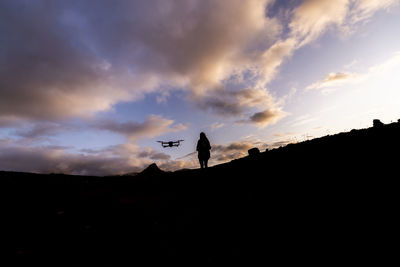 Silhouette man standing on land against sky during sunset