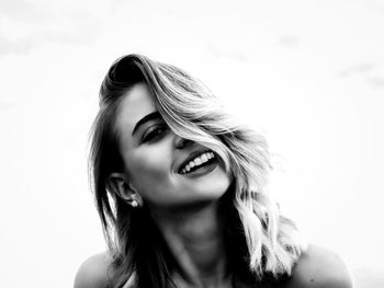 Close-up portrait of smiling young woman against white background