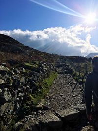 Rear view of person walking on landscape against sky