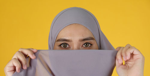 Portrait of man holding smart phone against yellow background