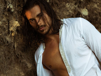 Portrait of young man standing against rock