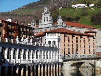 Old buildings over river against mountain