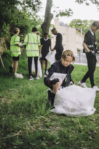 Volunteer kneeling by garbage bag collecting plastic