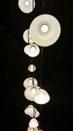 Low angle view of illuminated pendant lights hanging at night