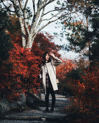 Woman standing by tree during autumn