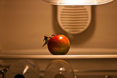 Apple over bottles in illuminated refrigerator