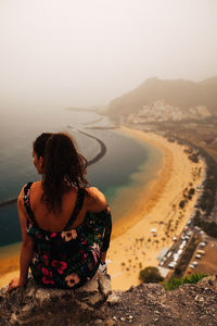 Rear view of woman looking at sea on cliff