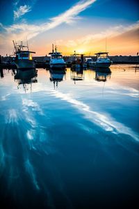 Boats moored in sea against sky during sunset