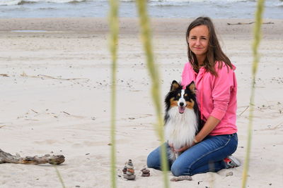 Portrait of woman with dog sitting on beach