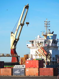 Cranes at commercial dock against clear sky